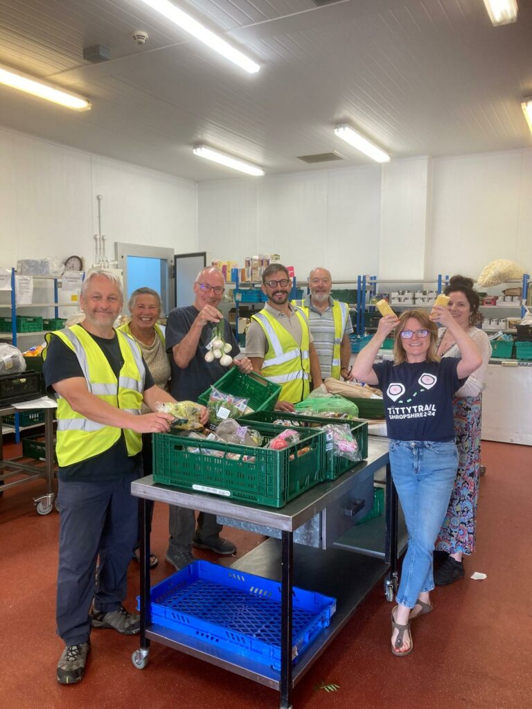 Staff and volunteers standing by a table of trays of food celebrating