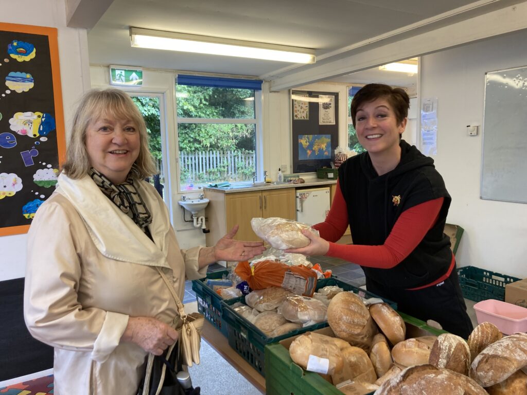 A volunteer offers a visitor surplus bread at a foodshare table